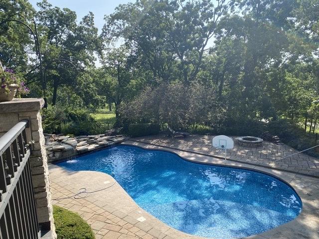 outdoor pool with a patio and a fire pit