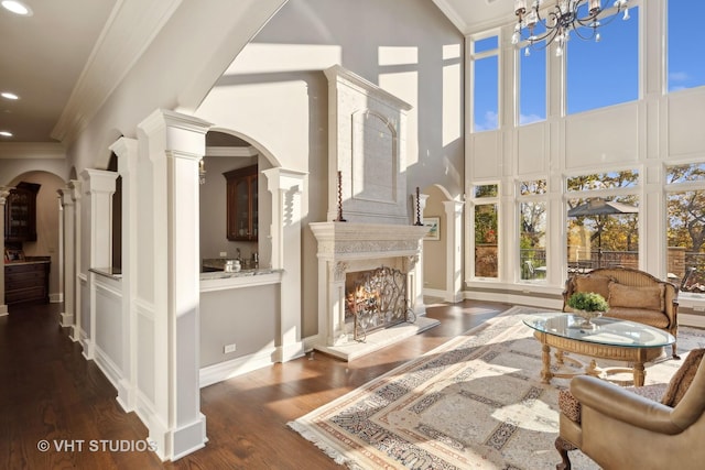 living area featuring recessed lighting, ornamental molding, a towering ceiling, and wood finished floors