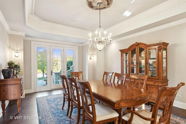 dining area with crown molding, a raised ceiling, dark wood finished floors, and a chandelier
