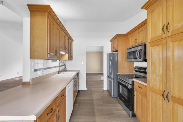 kitchen with a textured ceiling, stainless steel appliances, decorative backsplash, wood-type flooring, and sink