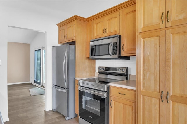 kitchen featuring light brown cabinetry, appliances with stainless steel finishes, light hardwood / wood-style floors, and decorative backsplash