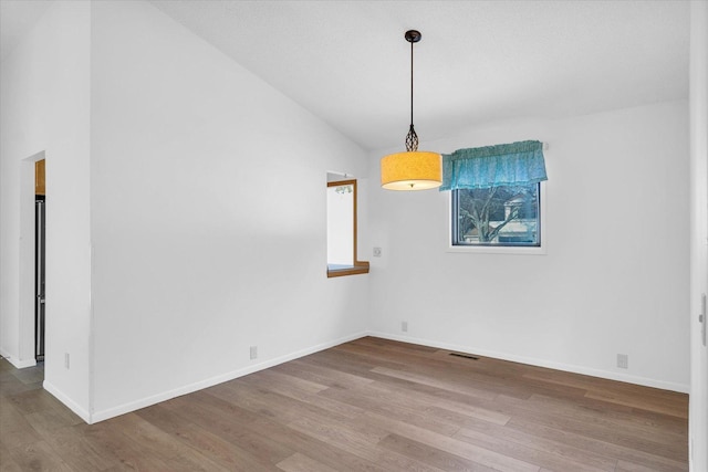 unfurnished dining area featuring wood-type flooring and vaulted ceiling