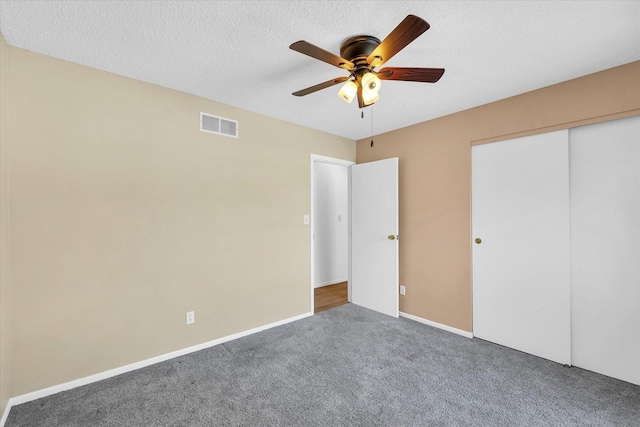 unfurnished bedroom with ceiling fan, a closet, carpet, and a textured ceiling