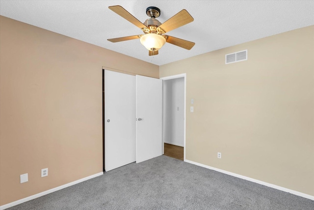 unfurnished bedroom with a closet, a textured ceiling, ceiling fan, and carpet flooring