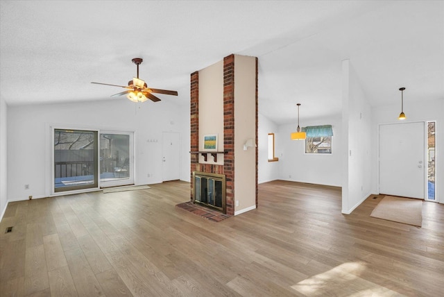 unfurnished living room with ceiling fan, light wood-type flooring, a brick fireplace, and vaulted ceiling