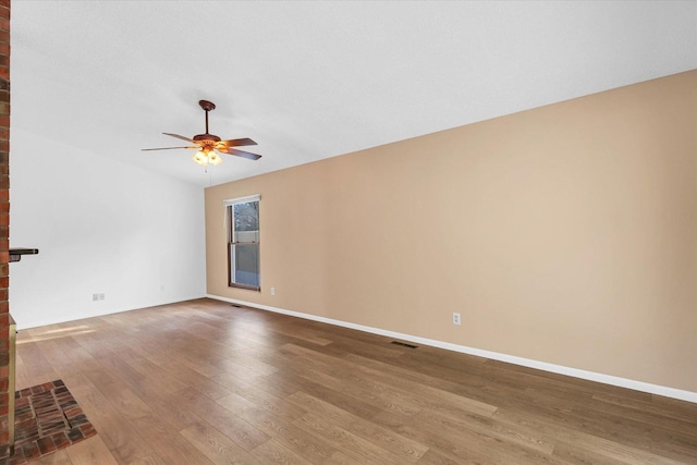 unfurnished living room featuring wood-type flooring, a brick fireplace, and ceiling fan