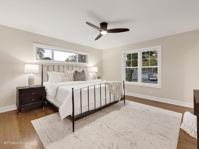 bedroom featuring ceiling fan, wood-type flooring, and multiple windows