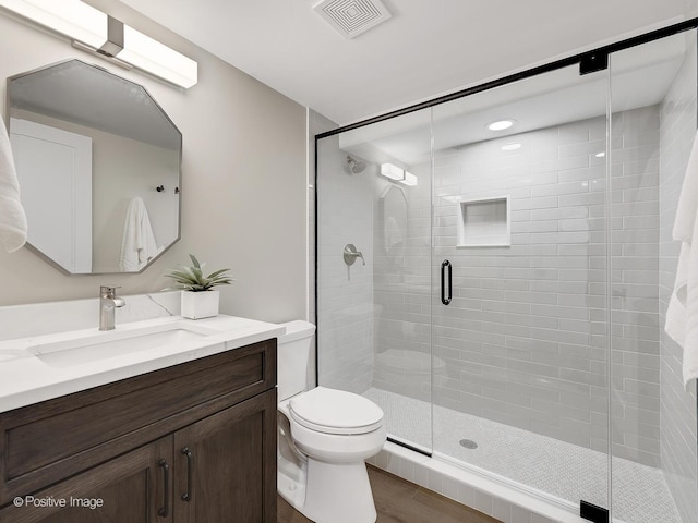 bathroom featuring walk in shower, vanity, hardwood / wood-style flooring, and toilet