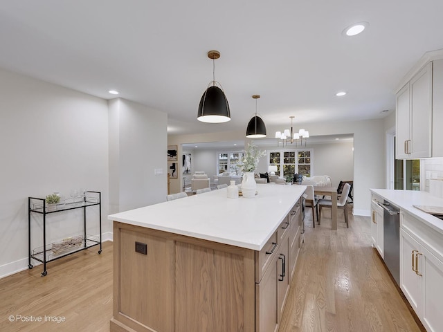 kitchen with dishwasher, hanging light fixtures, a kitchen island, white cabinets, and light hardwood / wood-style flooring