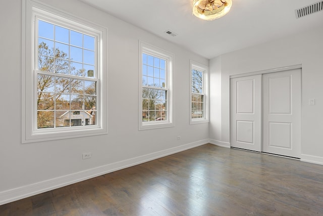 unfurnished bedroom with a closet and dark hardwood / wood-style flooring