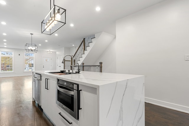 kitchen featuring sink, decorative light fixtures, and a kitchen island with sink