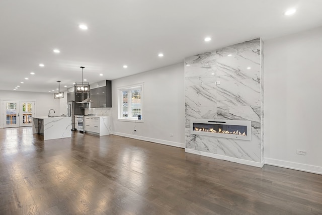 unfurnished living room featuring sink, a high end fireplace, and dark hardwood / wood-style floors