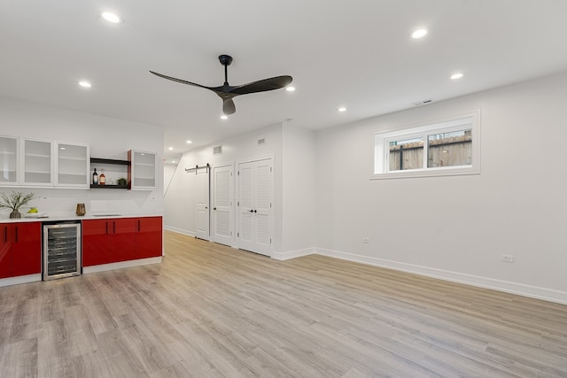 bar featuring beverage cooler, ceiling fan, and light hardwood / wood-style floors