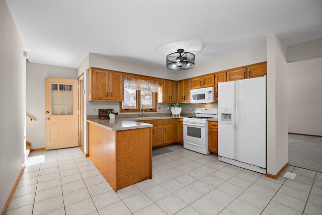 kitchen with white appliances, kitchen peninsula, sink, an inviting chandelier, and light tile patterned flooring