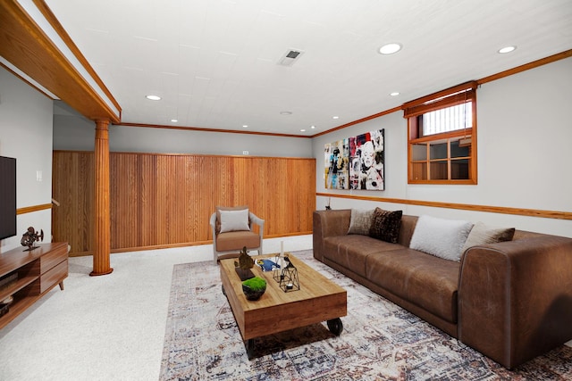 living room with wood walls, decorative columns, crown molding, and light colored carpet