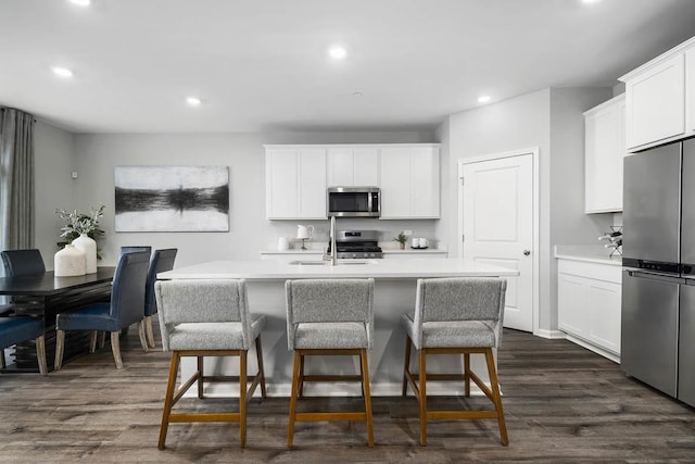 kitchen with white cabinetry, dark wood-type flooring, a kitchen island with sink, and appliances with stainless steel finishes