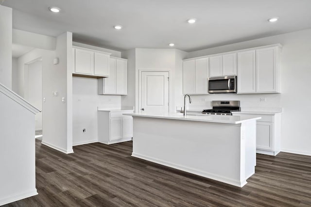 kitchen featuring stainless steel appliances, sink, white cabinetry, a center island with sink, and dark wood-type flooring