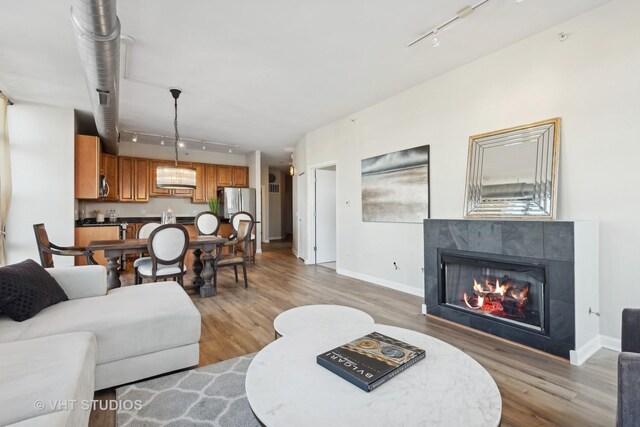 living room featuring a tile fireplace, rail lighting, and wood-type flooring