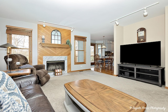 living room featuring track lighting, light colored carpet, and a premium fireplace