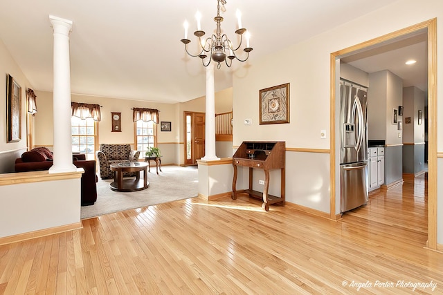 interior space featuring decorative columns, a chandelier, and light hardwood / wood-style flooring