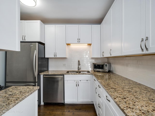 kitchen with sink, stainless steel appliances, white cabinetry, and backsplash