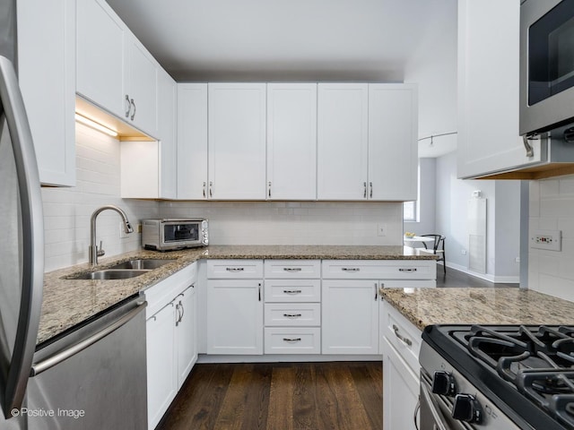 kitchen with white cabinets, stainless steel appliances, light stone counters, and sink