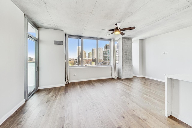 empty room with ceiling fan and light hardwood / wood-style flooring