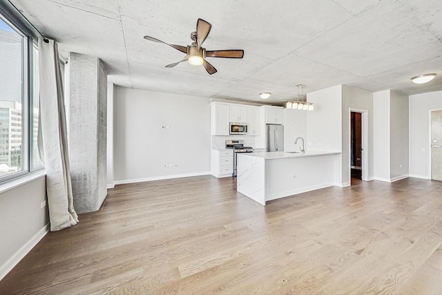 unfurnished living room with ceiling fan, sink, and light hardwood / wood-style flooring