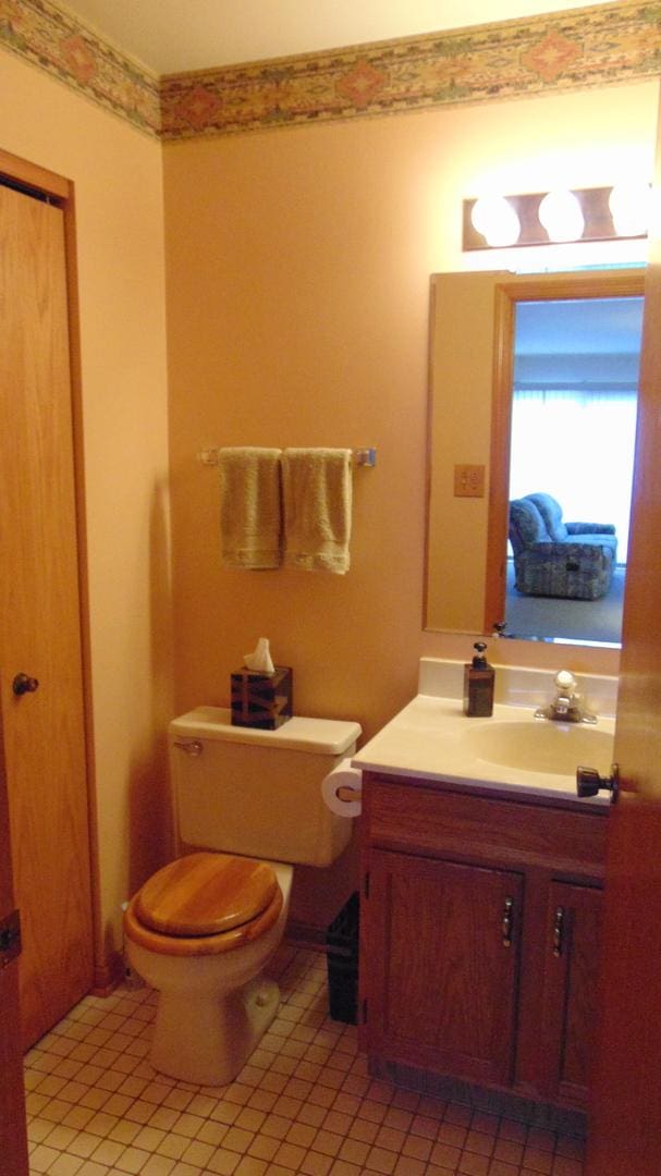 half bathroom with toilet, tile patterned flooring, and vanity