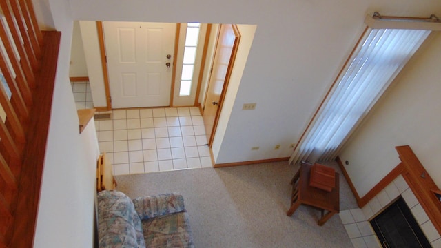 tiled entrance foyer with carpet, stairway, a fireplace, and baseboards