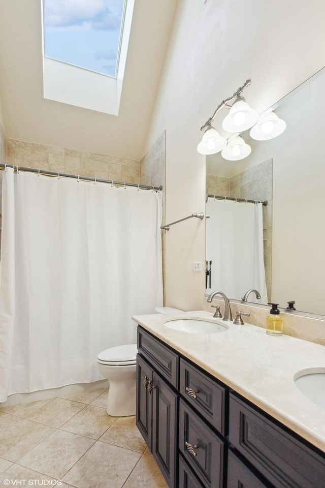 bathroom with vaulted ceiling with skylight, tile patterned floors, vanity, and toilet