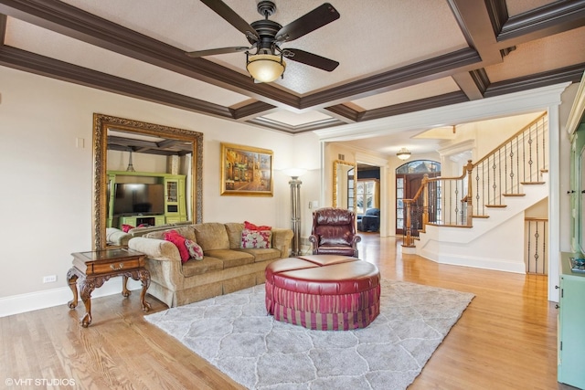 living room featuring beamed ceiling, light wood-type flooring, ceiling fan, crown molding, and coffered ceiling