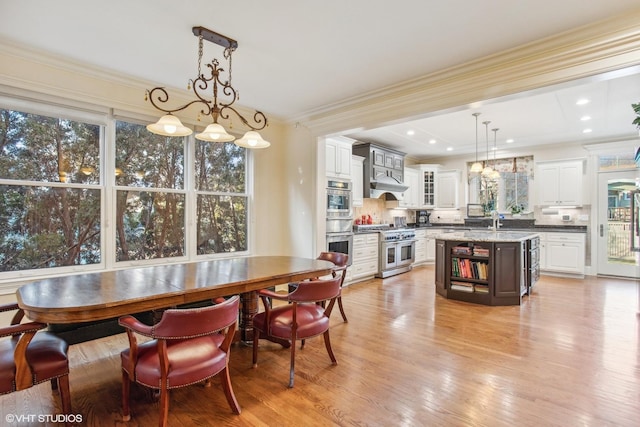 dining room with light hardwood / wood-style floors, sink, crown molding, and a healthy amount of sunlight