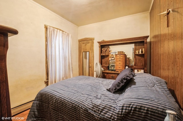 bedroom with ornamental molding, a baseboard heating unit, and wood walls