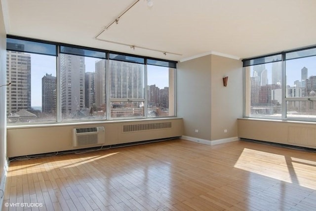 unfurnished room with crown molding, a wall mounted AC, and light hardwood / wood-style flooring