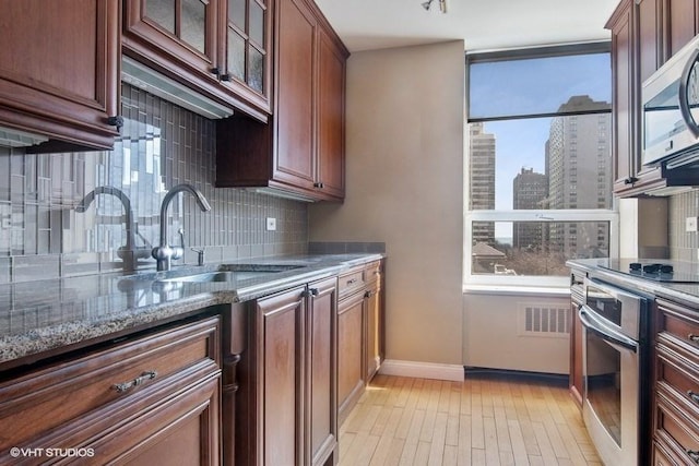 kitchen with sink, stainless steel appliances, dark stone counters, and plenty of natural light