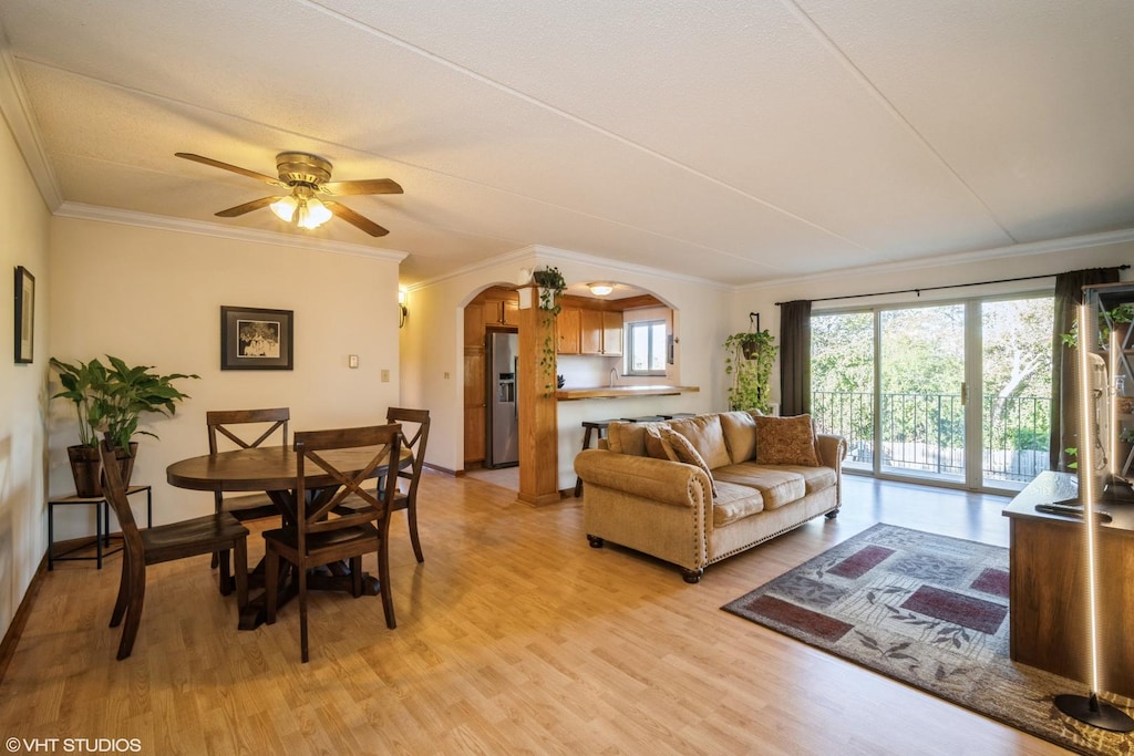 living room with light wood-type flooring, ceiling fan, and ornamental molding