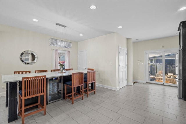 kitchen featuring light stone countertops, beverage cooler, pendant lighting, and a breakfast bar