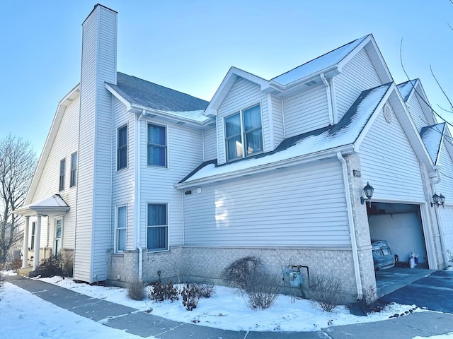 snow covered property with a garage