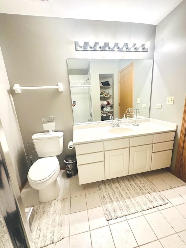 bathroom featuring toilet, tile patterned floors, walk in shower, and vanity