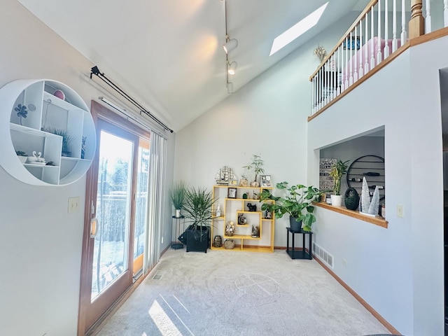 interior space with carpet, rail lighting, and vaulted ceiling with skylight