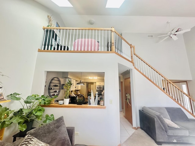 tiled living room with ceiling fan and lofted ceiling with skylight