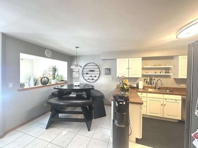 kitchen featuring sink, pendant lighting, wood counters, and light tile patterned flooring