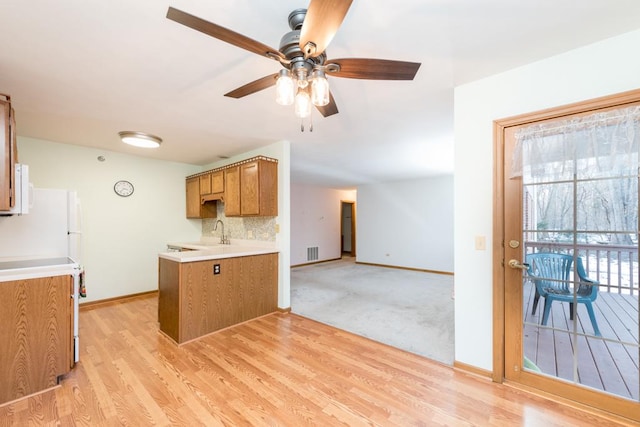 kitchen featuring light hardwood / wood-style floors, ceiling fan, backsplash, range, and sink