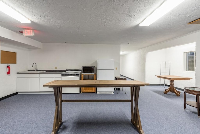 recreation room featuring sink, a textured ceiling, and dark colored carpet