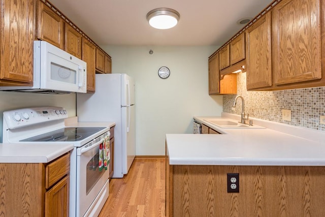 kitchen featuring kitchen peninsula, backsplash, white appliances, light hardwood / wood-style flooring, and sink