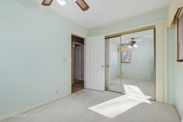 unfurnished bedroom featuring ceiling fan, light colored carpet, crown molding, and a closet