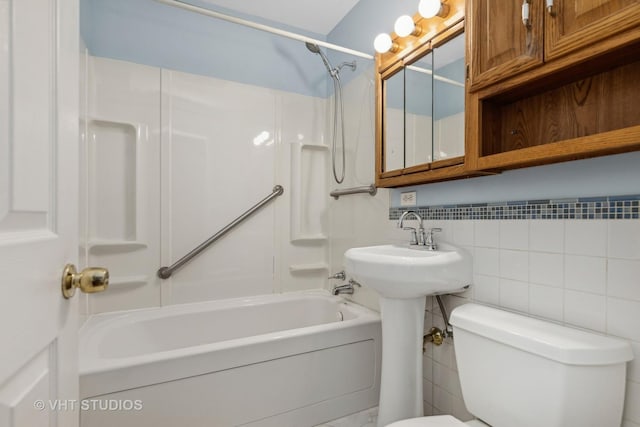 bathroom with shower / tub combination, toilet, and tile walls