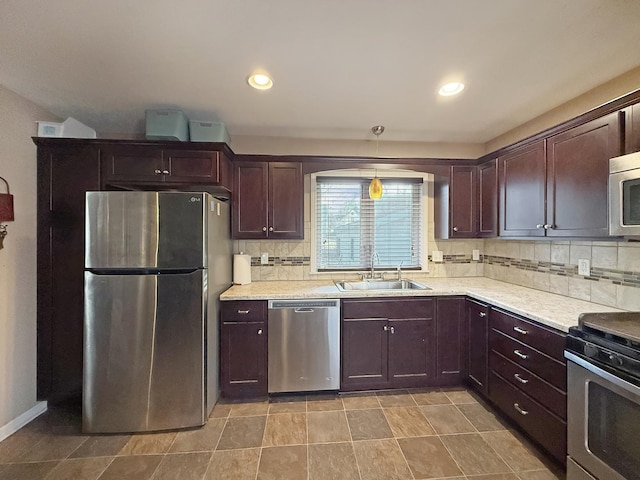 kitchen with appliances with stainless steel finishes, pendant lighting, decorative backsplash, and sink