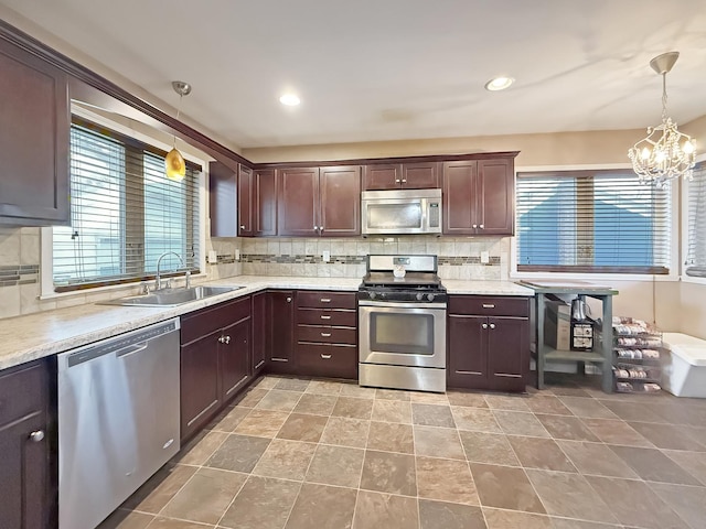 kitchen with sink, an inviting chandelier, backsplash, pendant lighting, and appliances with stainless steel finishes